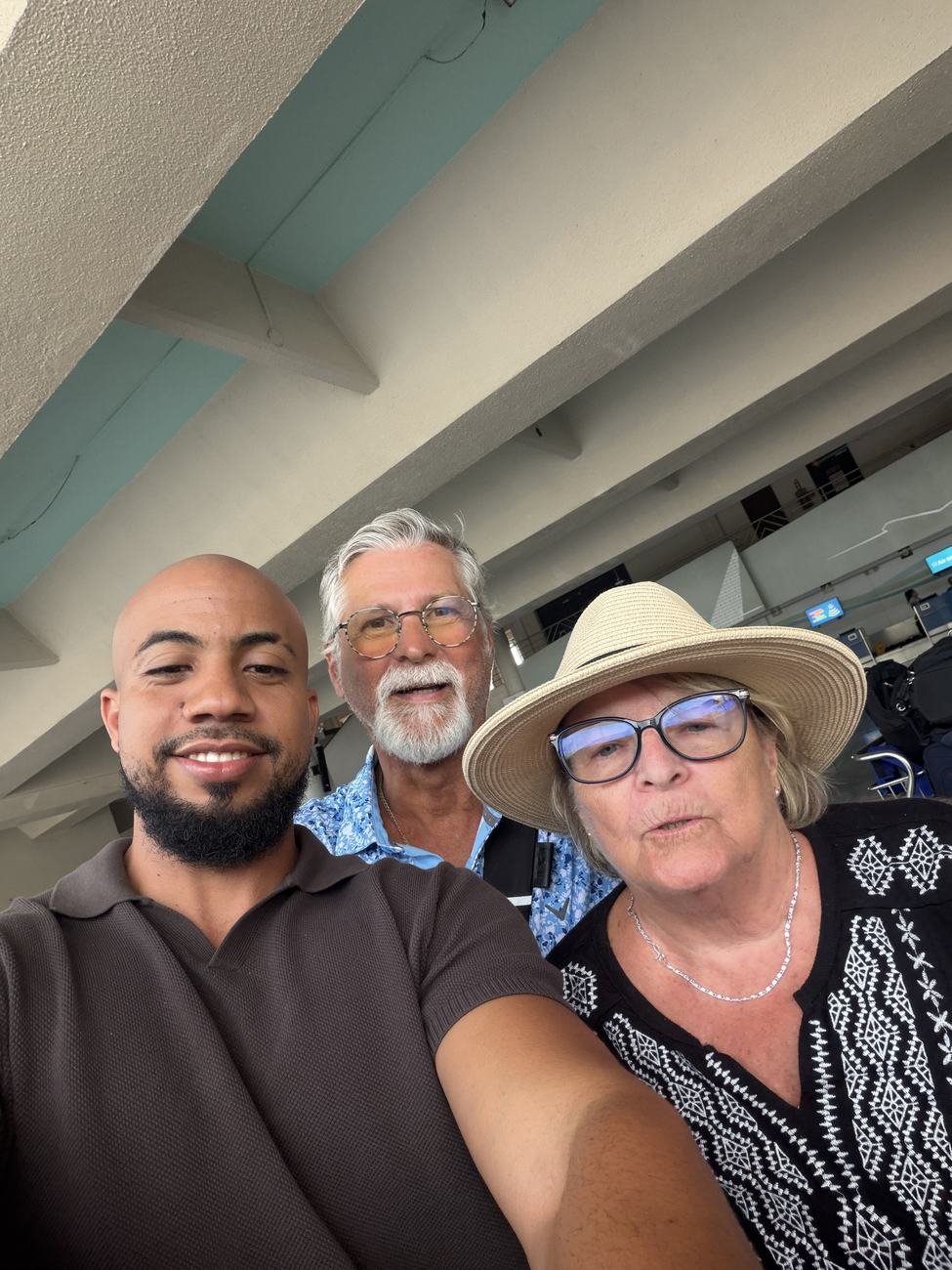 Three people smiling together at an airport terminal
